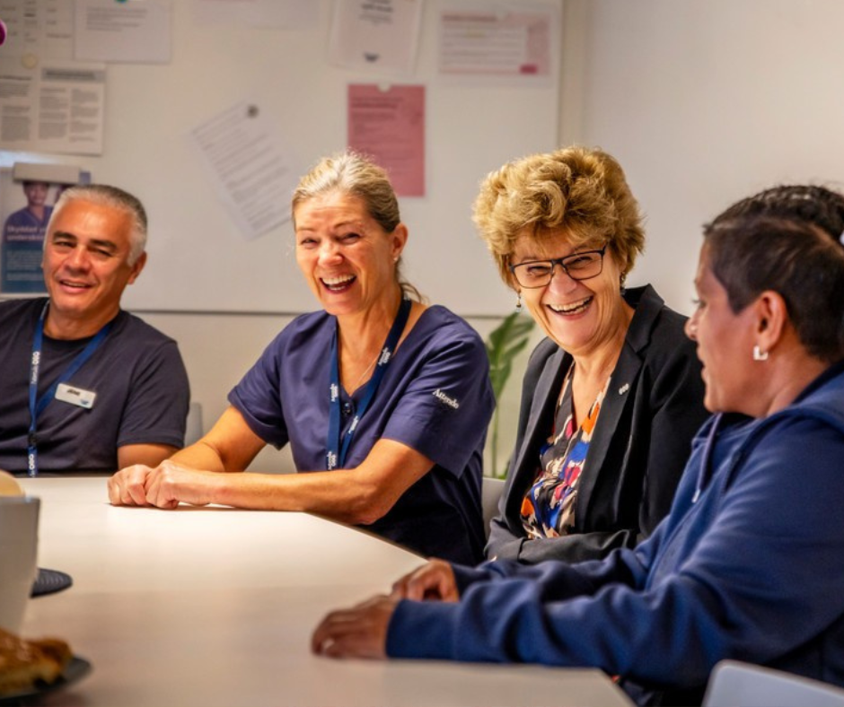 Fyra medarbetare skrattar tillsammans i personalrummet