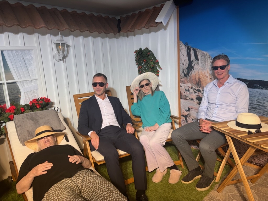 Ministern och de &auml;ldre testar tillsammans solrummet, sitter i solglas&ouml;gon i solstolar med sommarlik omgivning