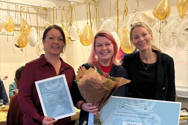 En leende Jossan Beckert med en stor check i handen, omringad av chefer som hyllar henne