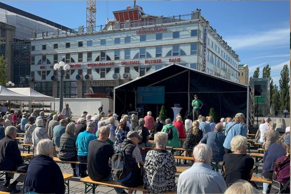 Föreläsning på scen och lyssnande seniorer på bänkar framför