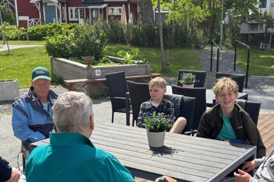 Två äldre män och två pojkar sitter tillsammans och samtalar.
