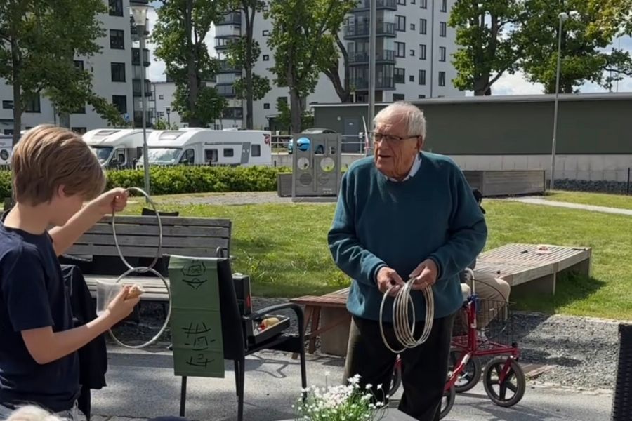 Äldre man trollar med ringar framför en av eleverna