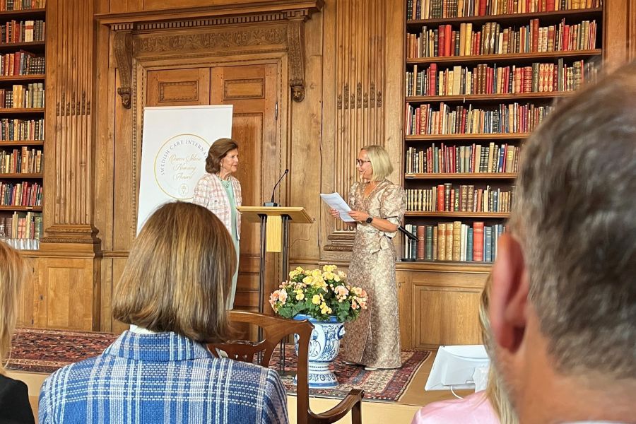 drottning silvia och socialministern samtalar på podie