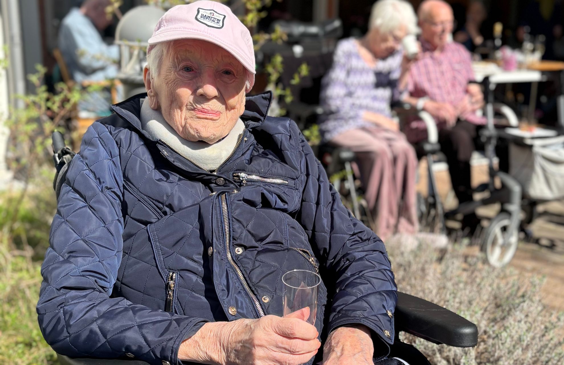 Kvinna som bor på äldreboende dricker bubbel utomhus på våren