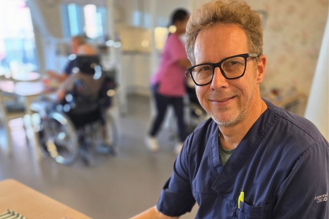 Michael i matsalen på äldreboendet, boenden och personal skymtar i bakgrunden